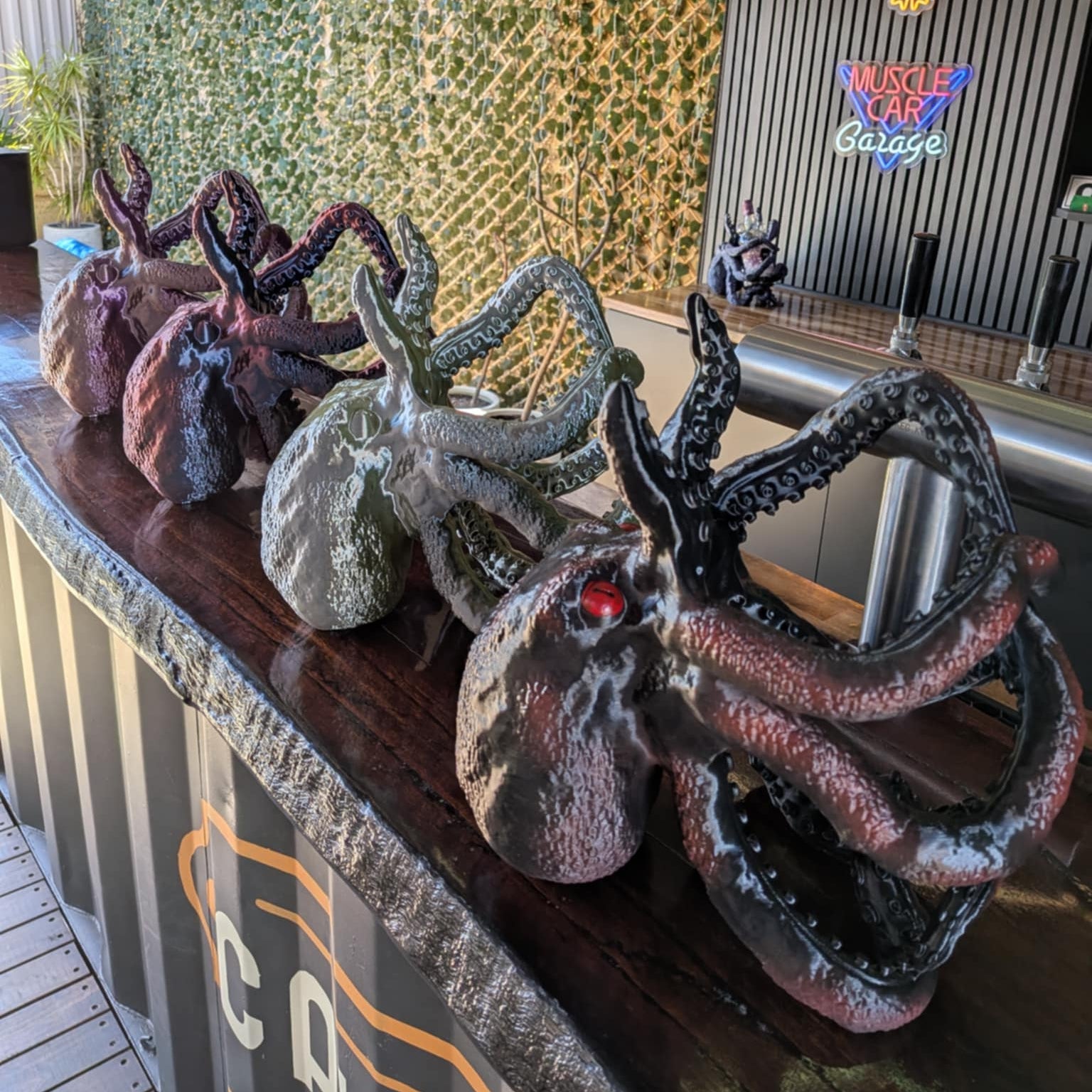 Decorative metal octopus sculptures on a bar counter with a Jim Beam sign in the background.